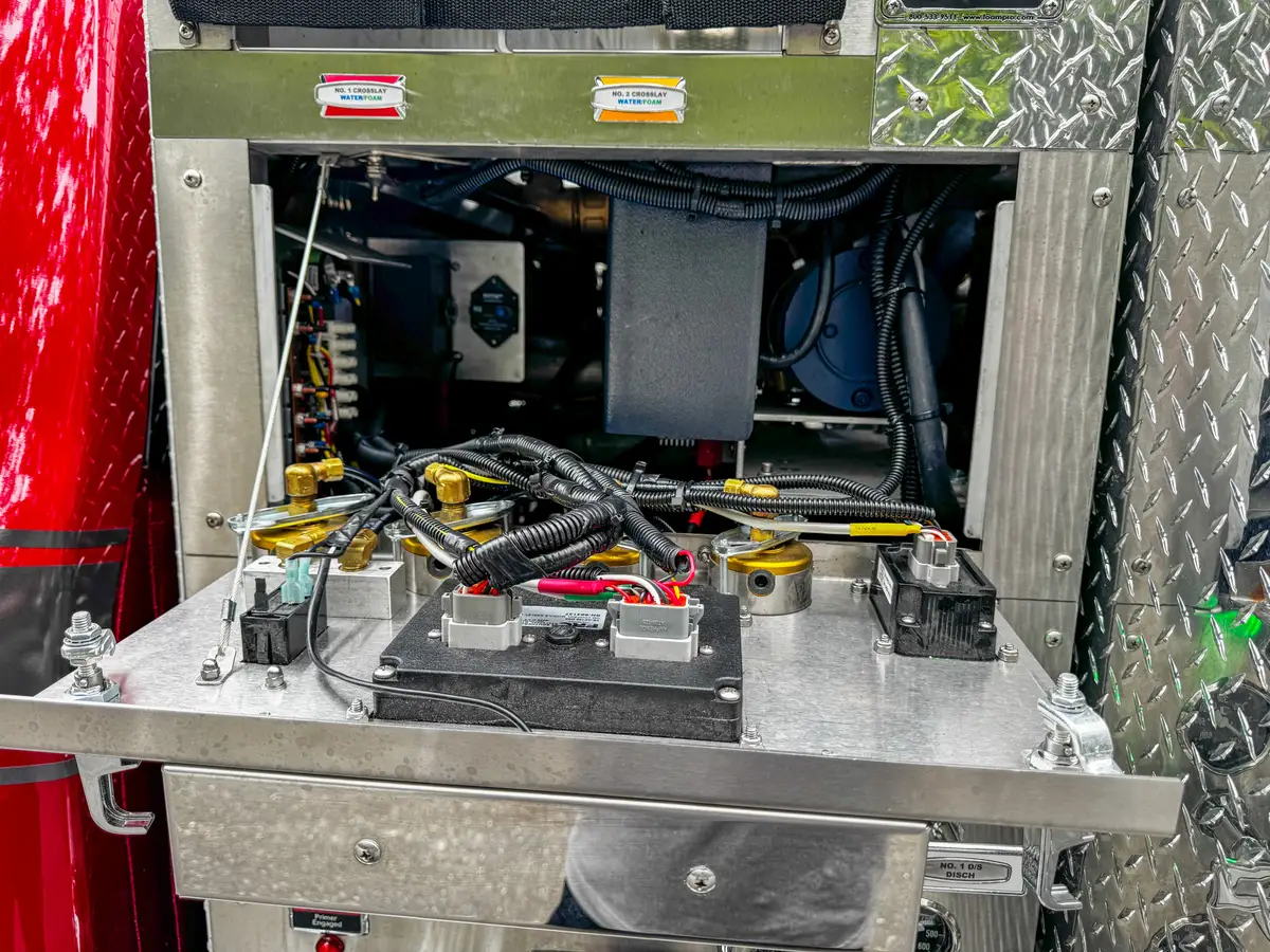Service compartment interior close-up with hoses, wiring, and mounted components.